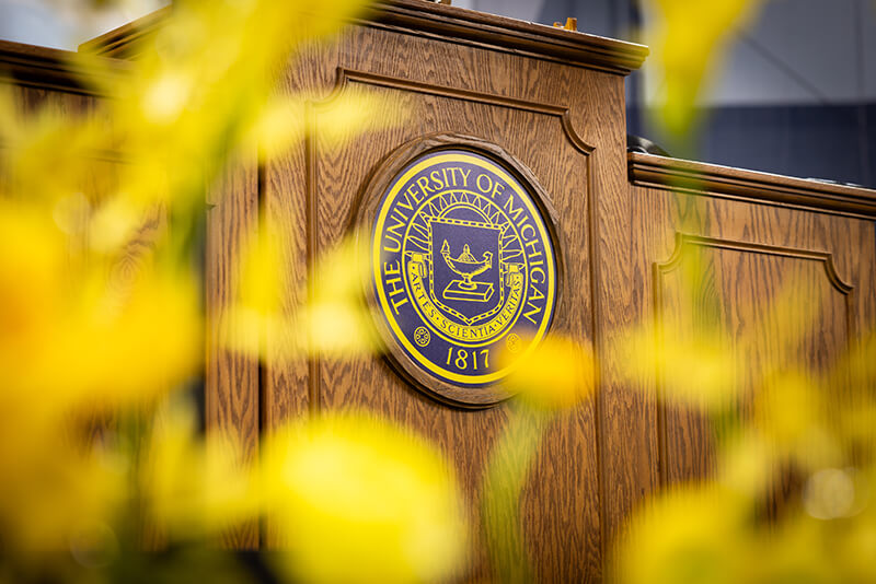 A wooden lectern with the University of Michigan seal